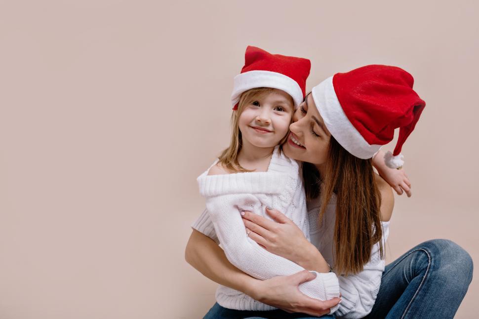 Free Image of Indoor studio portrait of glad woman and her little charming daughter 