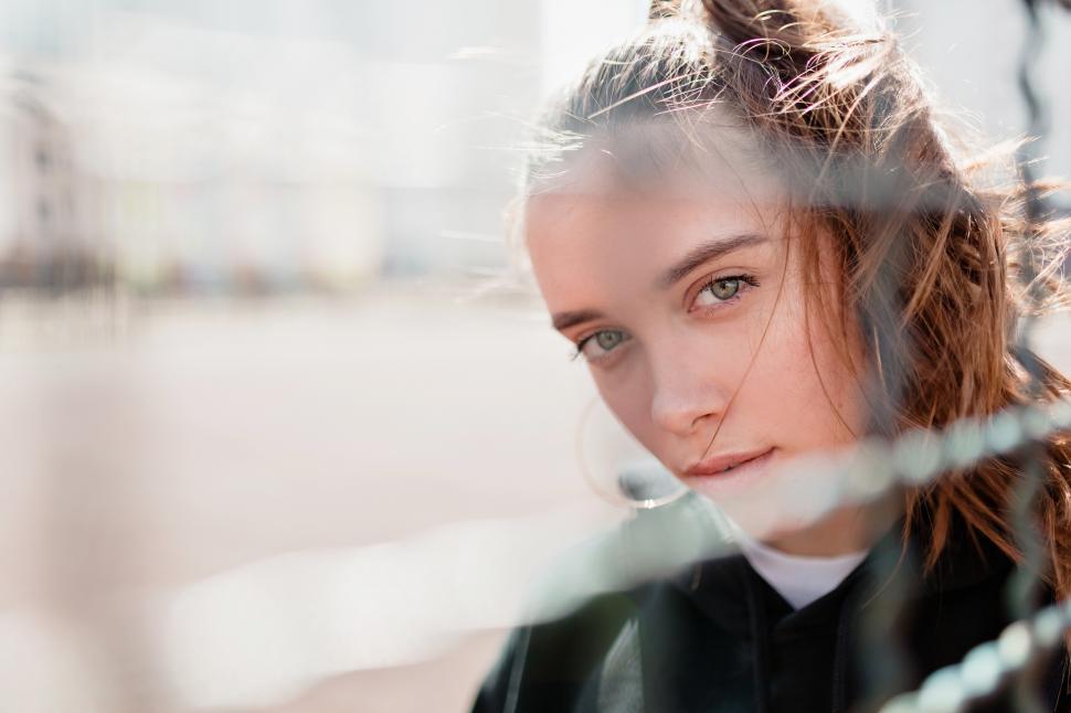 Free Image of Pretty woman with long hair looking through fence 