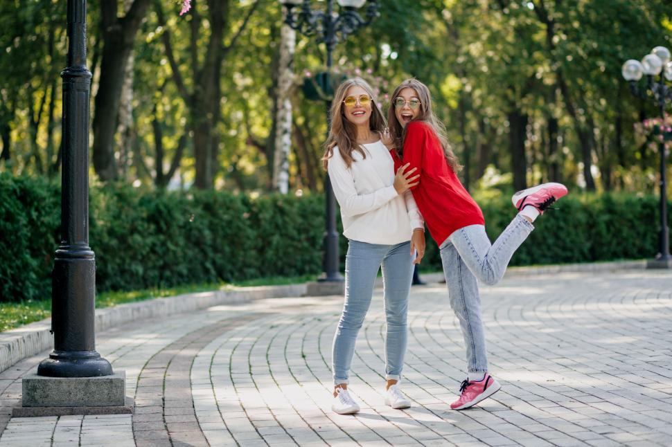 Free Image of Full-lenght outdoor portrait of two friendly happy girls in public park 