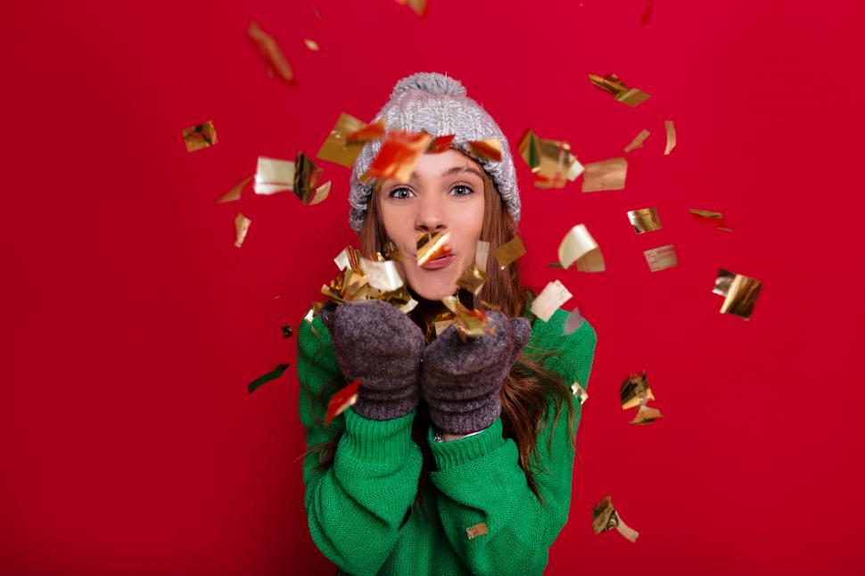 Free Image of Woman on red background celebrating New Year with confetti 