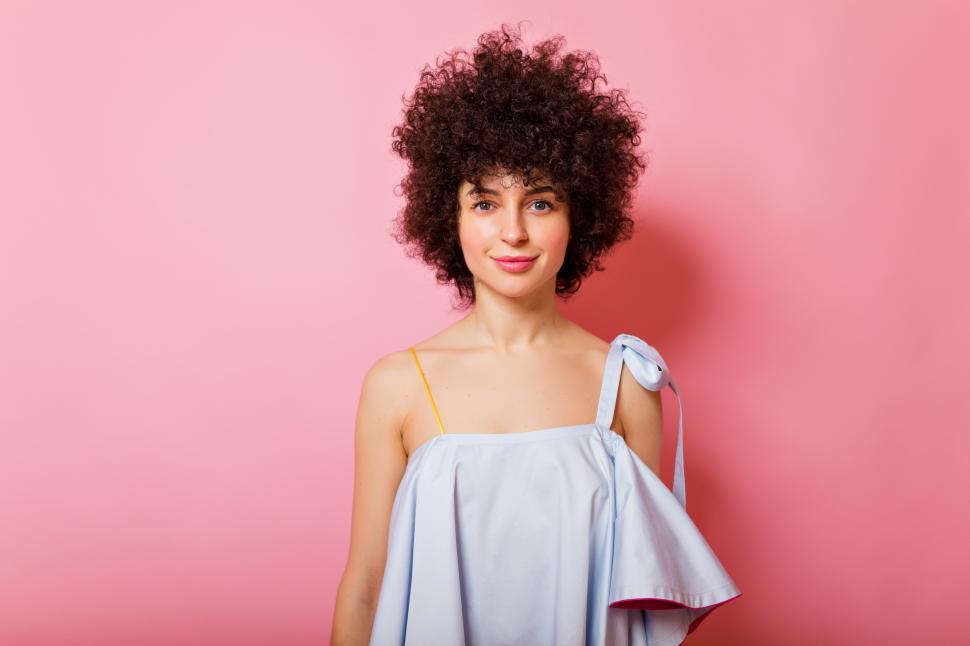 Free Image of Pretty woman with short curly hair wears blue shirt smiles at camera 
