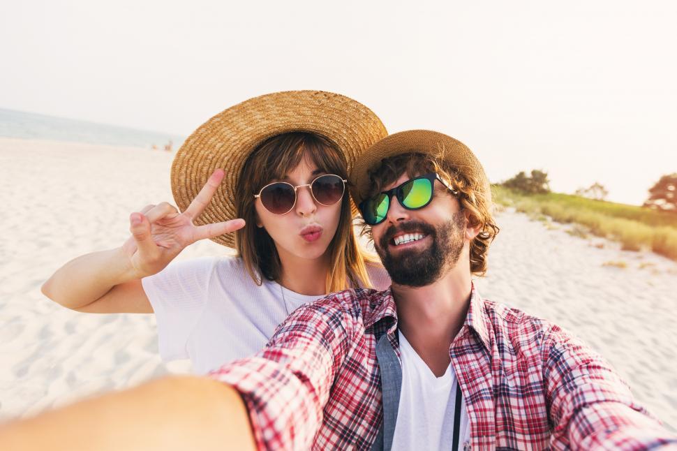 Free Image of Traveling couple in love taking a selfie on phone at the beach 