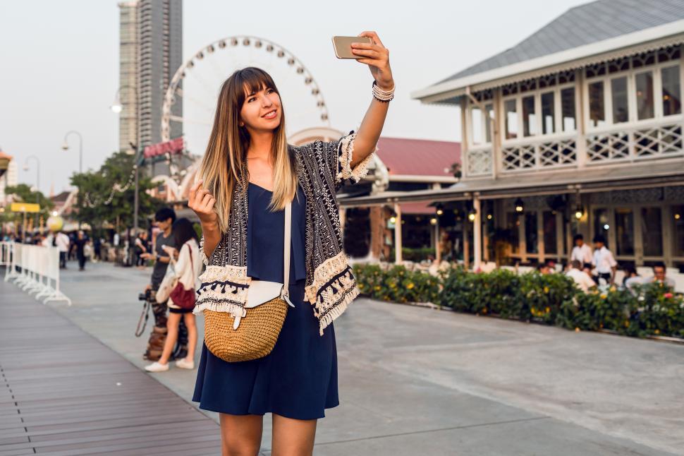 Free Image of Happy woman making self portrait with ferris wheel in the background 