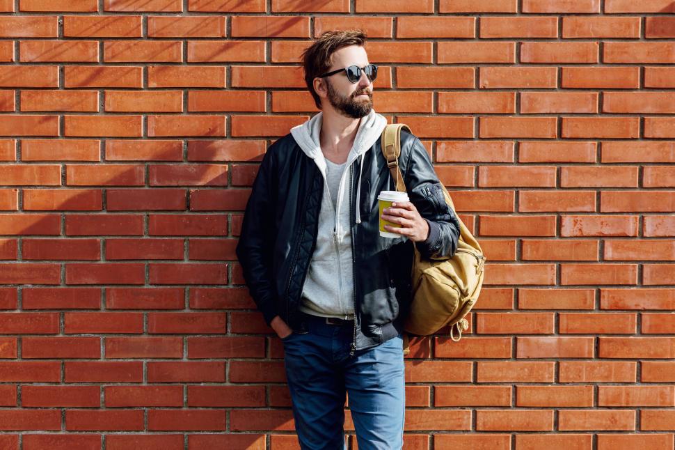 Free Image of Outdoor fall or winter portrait of handsome man with beard, grey hoodie and leather jacket 