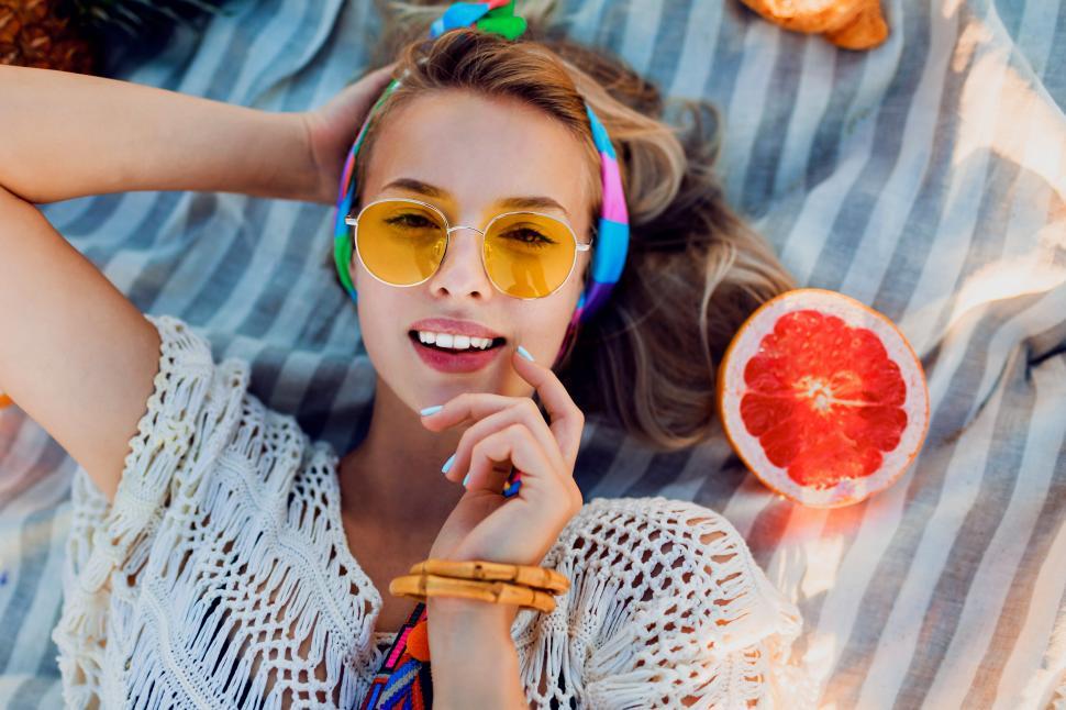 Free Image of Excited girl on beach towel. Boho accessories. 