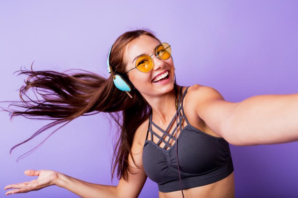 Free Image of Carefree sportive woman playing with hairs and making self portrait by mobile phone  during training 