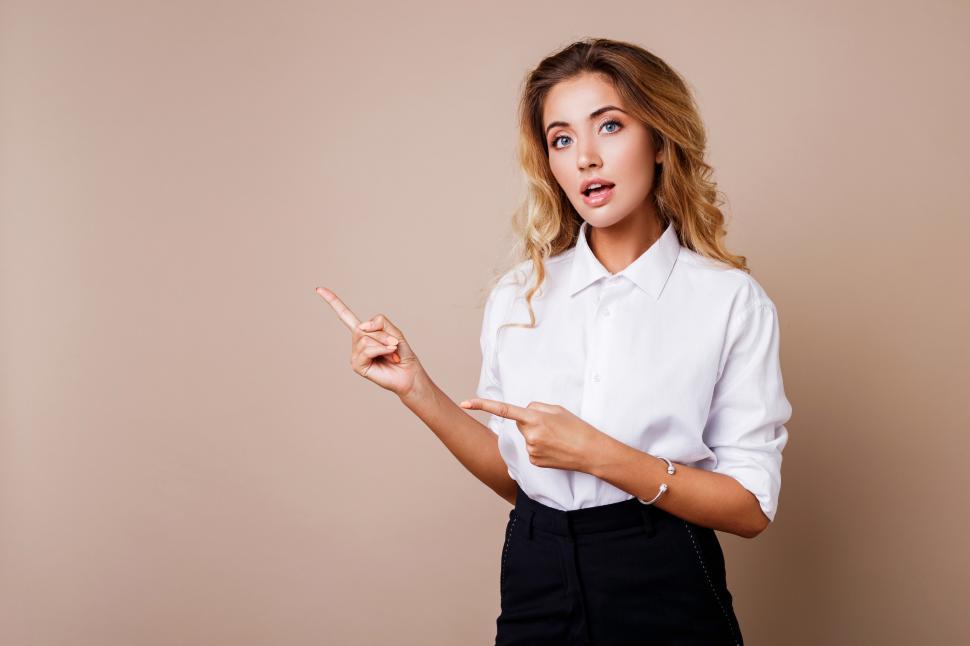 Free Image of Blond business woman pointing up and looking at camera 