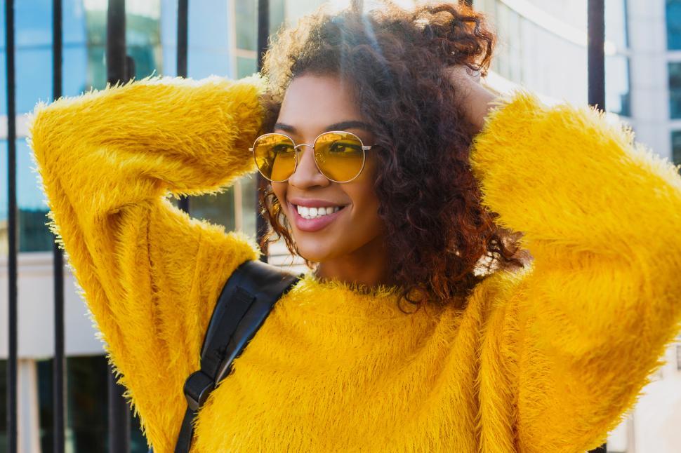 Free Image of Woman in yellow with backpack standing in city 
