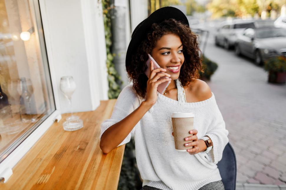 Free Image of Woman in stylish casual outfit relaxing outdoor in city cafe, chatting on mobile phone 