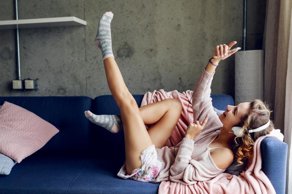 Free Image of Happy woman in pink sweater listening music by earphones 