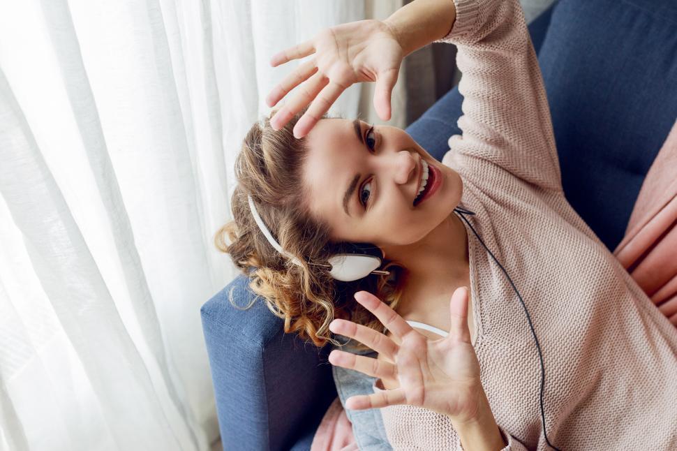 Free Image of Happy girl with blonde wavy hairstyle lying on blue sofa 