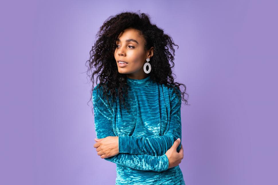 Free Image of Confident woman in velvet dress with wavy hair posing on blue violet background 