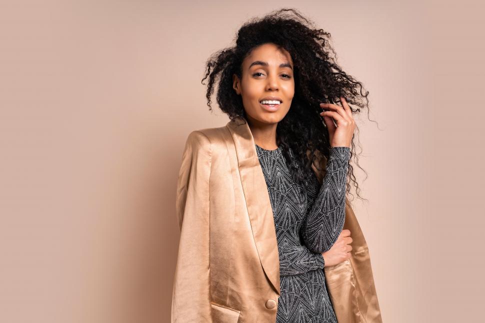 Free Image of Woman in golden silk jacket and shiny dress posing in studio 