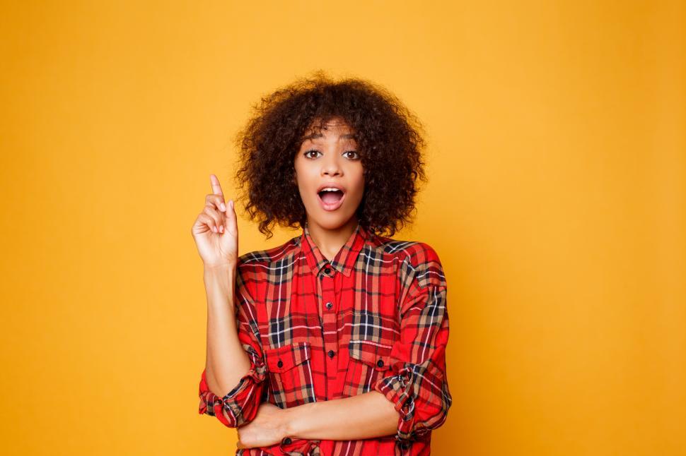 Free Image of Woman in red shirt looking on camera  and pointing finger up on copy space 