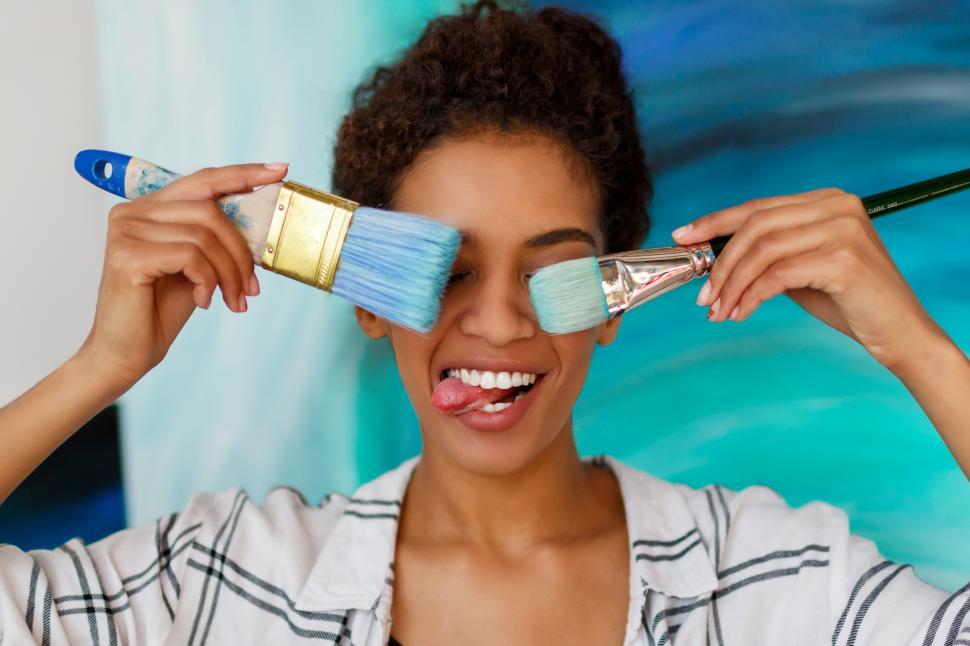 Free Image of Female artist holding brushes and making faces 