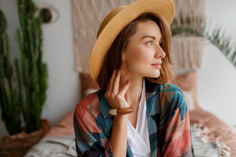 Free Image of Woman in straw hat chilling over bohemian interior 