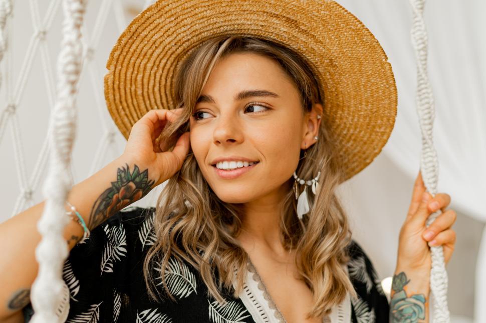 Free Image of Lady sitting on hanging swing, wearing straw hat 