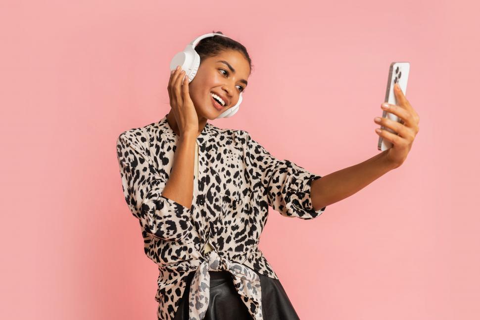 Free Image of Woman listening music by earphones making self portrait by mobile phone 