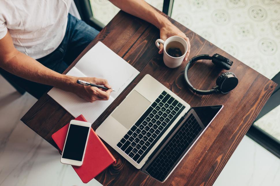 Free Image of Man using laptop, making notes 