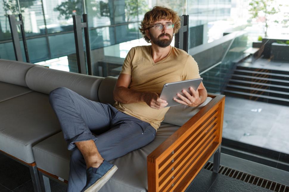 Free Image of Man sitting on sofa using tablet 