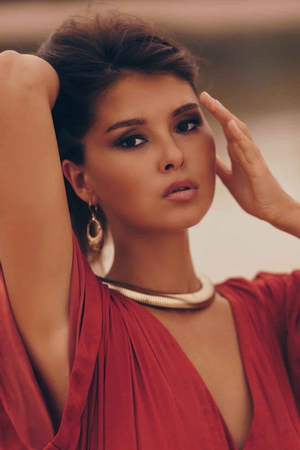 Free Image of Woman in golden earrings and necklace posing on the beach 