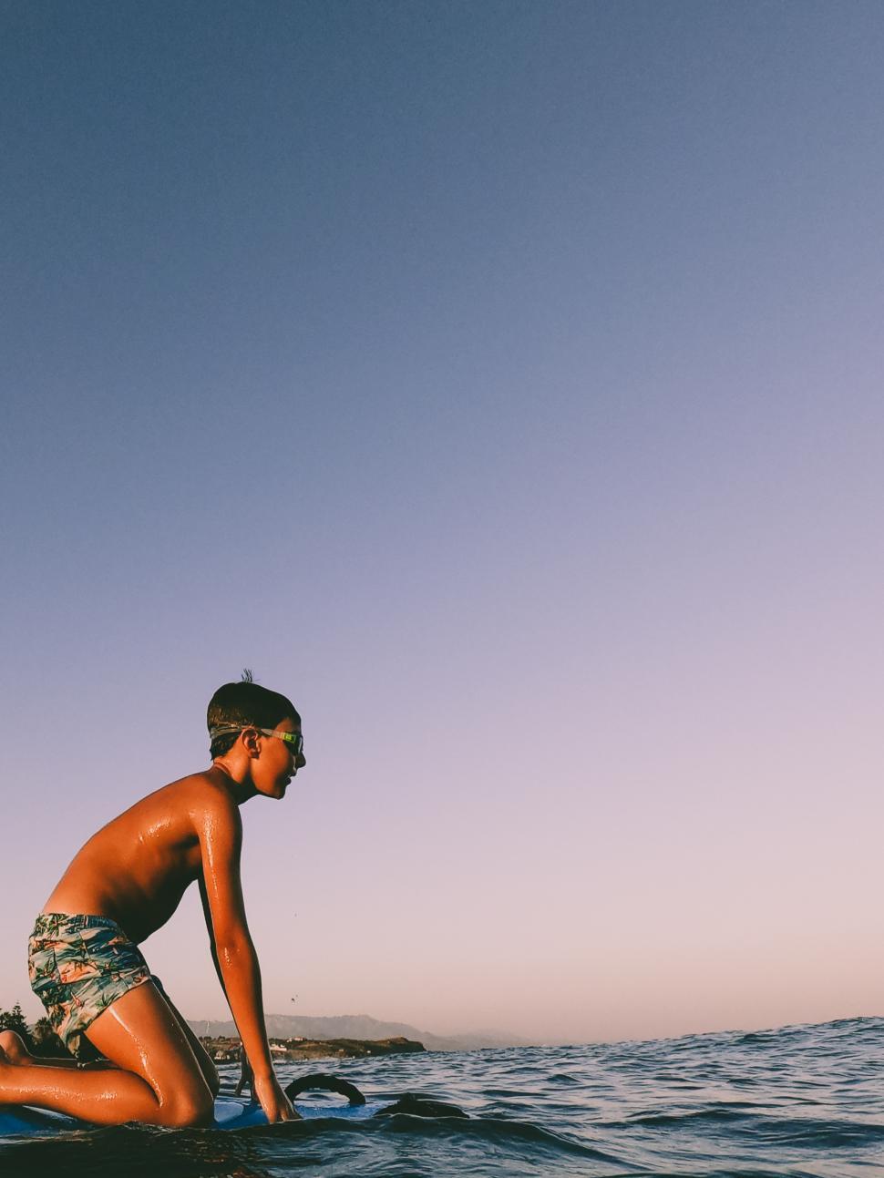 Free Image of a young kid on a surfboard in the ocean 