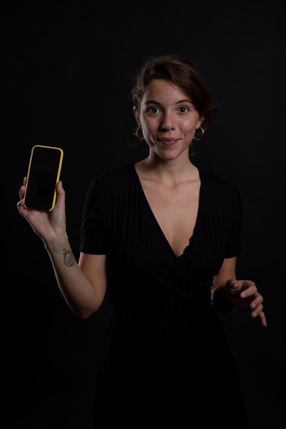 Free Image of A young woman holding up a smartphone in a studio shot 