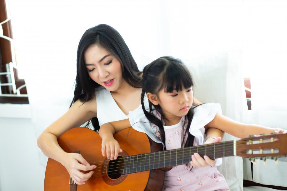 Free Image of Happy family. Mother and daughter playing guitar. 