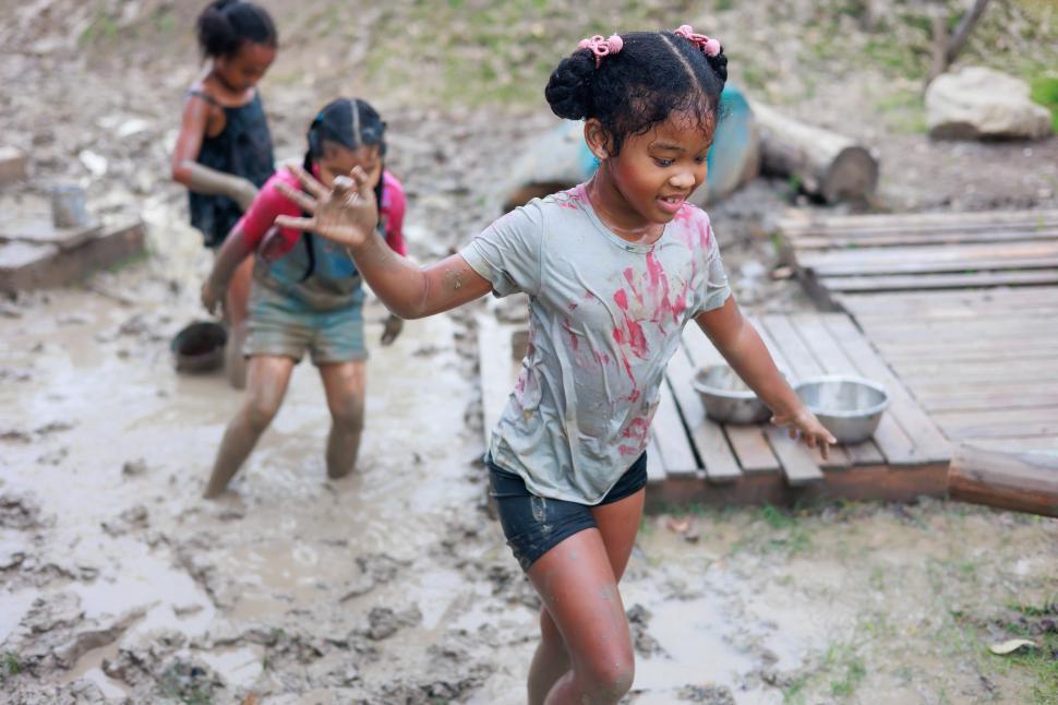 Free Image of Happy dirty girls run in mud puddle 