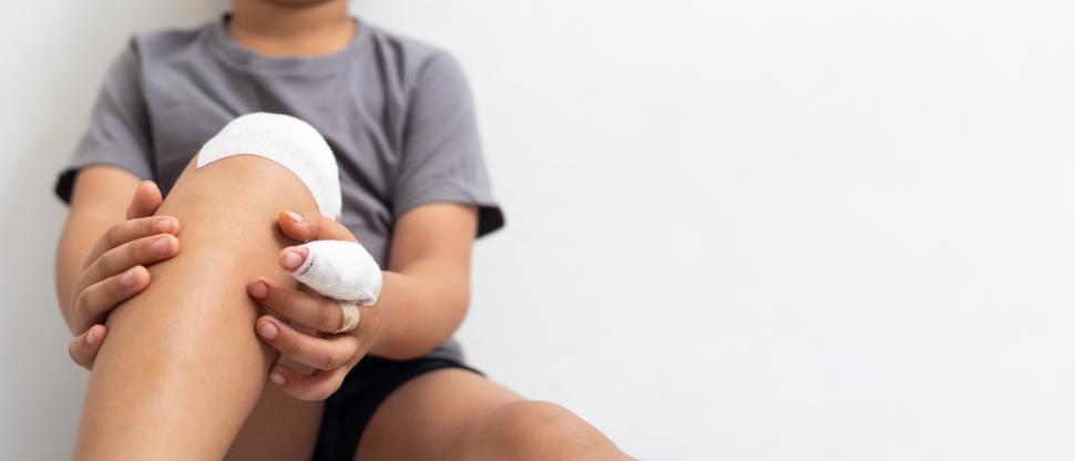 Free Image of Kid with injuries to knee and finger. Bandaged boy. 