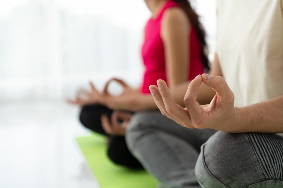 Free Image of A pregnant woman meditates with her husband in a living room. 