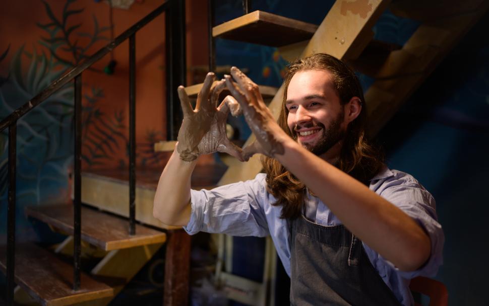 Free Image of Pottery artist making heart with clay covered fingers 