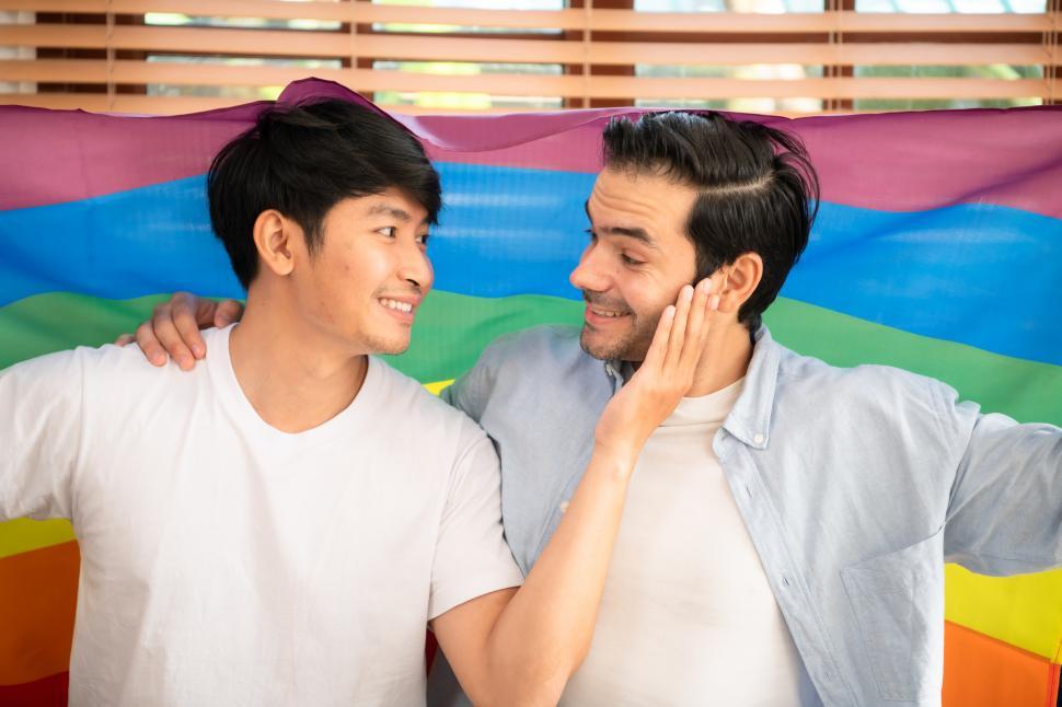 Free Image of Two men sitting in front of a rainbow pride flag - LGBT pride 