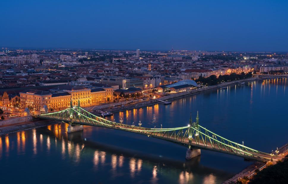 Free Image of Large Bridge Crossing River Next to Urban Cityscape 