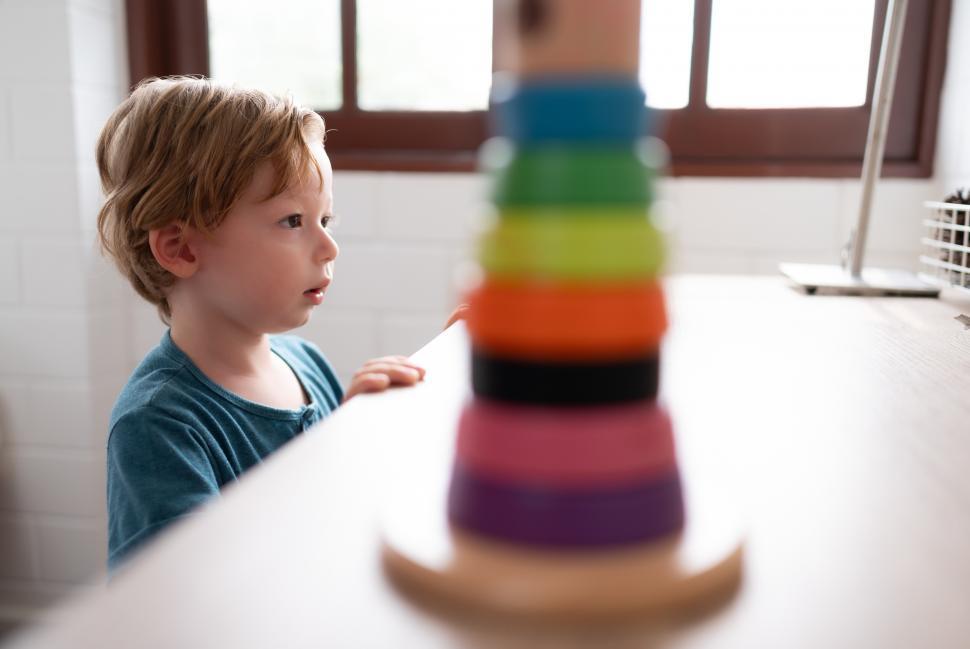Free Image of Little boy in his bedroom looking at toys, with new toy in the foreground 
