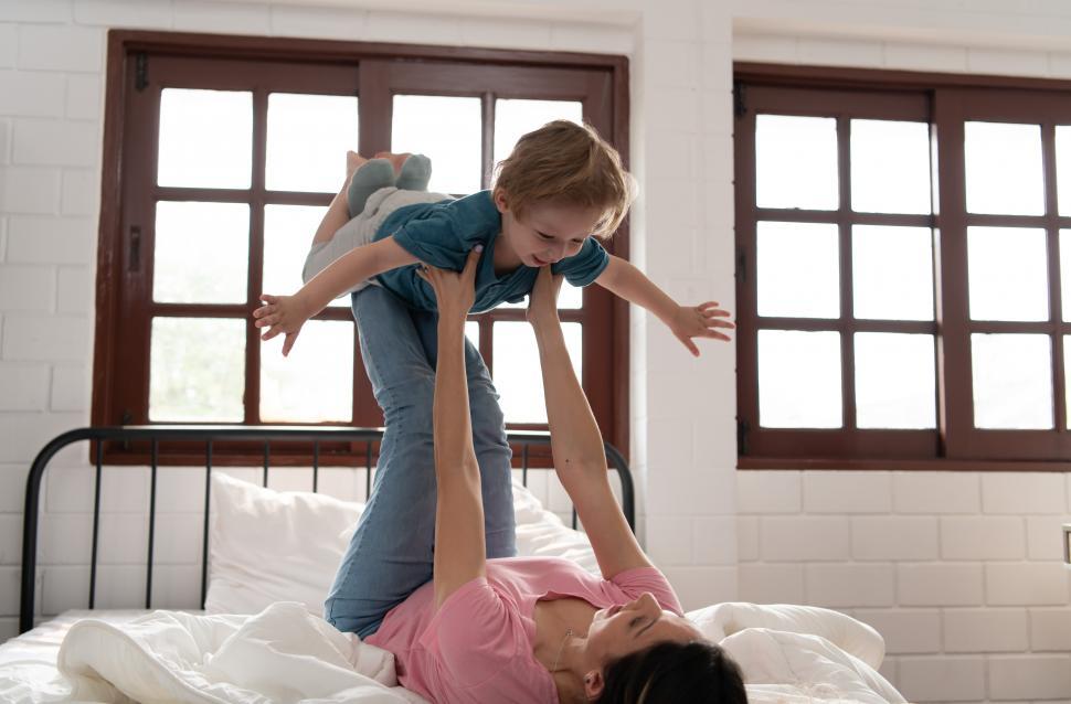 Free Image of Little boy flying with mom using her legs to help him fly high  
