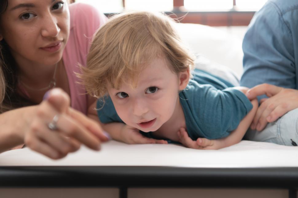 Free Image of Little boy waking up from his nap surrounded by his family 