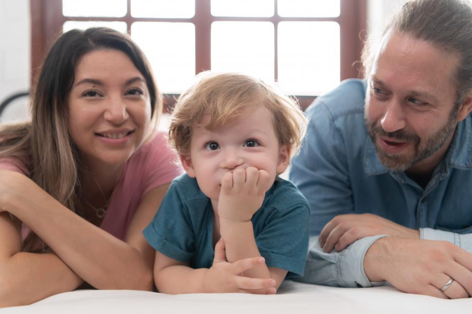 Free Image of Little boy with his family - he's watching something, with his head on his hand 