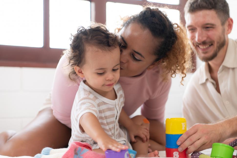 Free Image of Mother and father being affectionate with little girl. Happy Family. 
