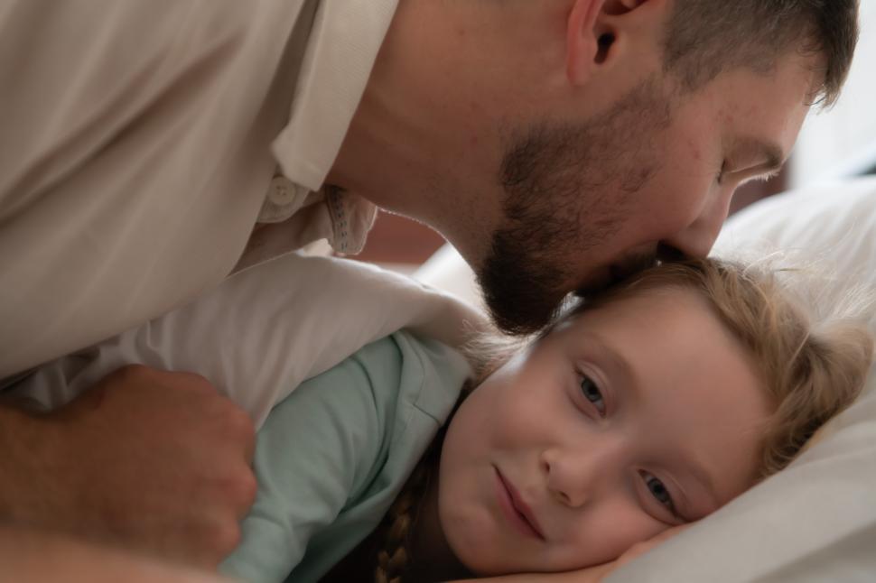 Free Image of Father kisses his daughter good night at the end of a long day 