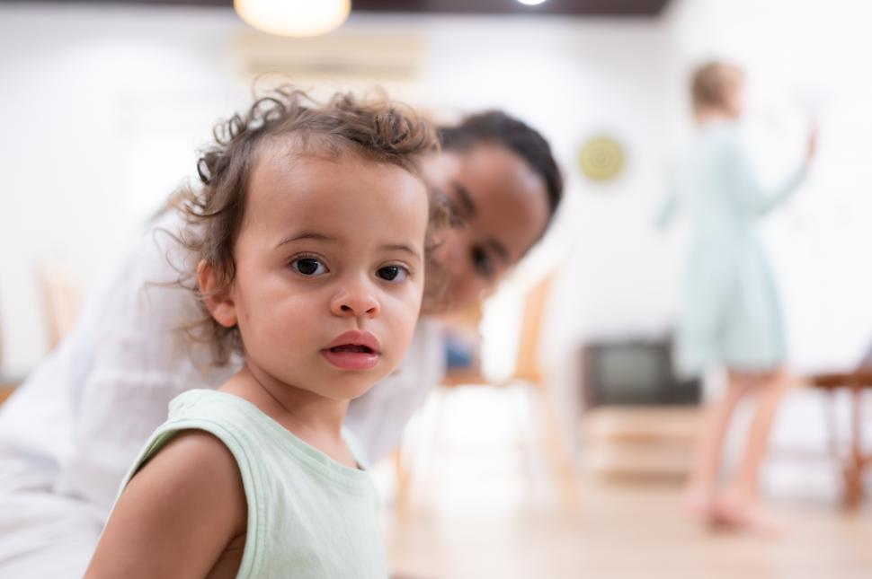 Free Image of Portrait of cute little girl looking at camera while her mother looks on 