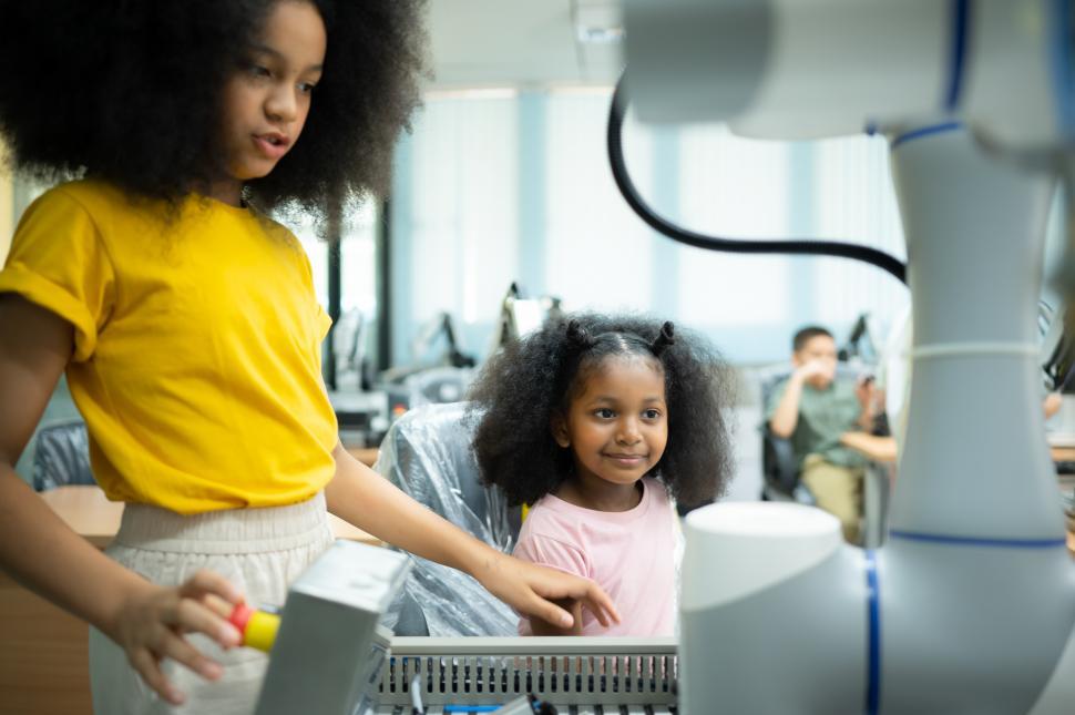 Free Image of Two young girls learning how to build and control a robotic arm in a STEM science lab 