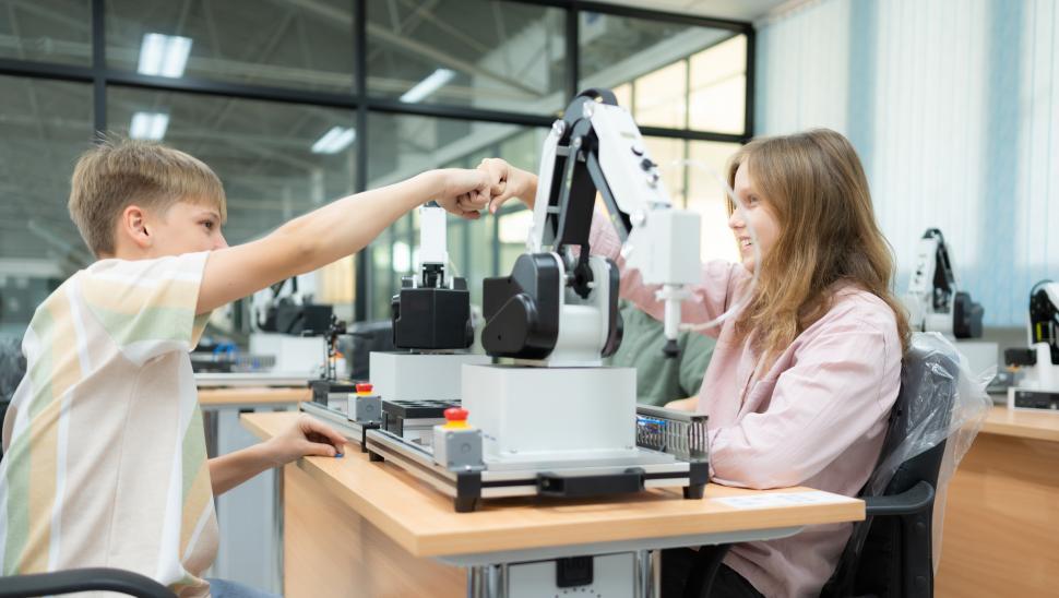 Free Image of Students celebrate milestone while working with robotic arm in science lab 