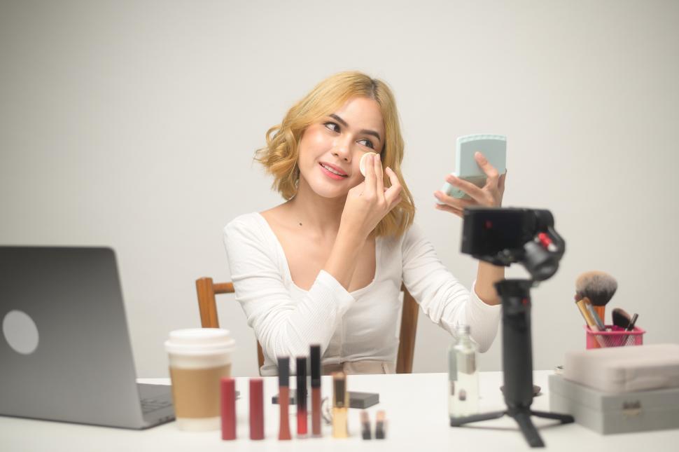 Free Image of Woman beauty blogger working with laptop presents cosmetics 