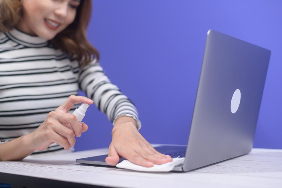 Free Image of Woman with sanitizing alcohol spray for computer keyboard cleaning 