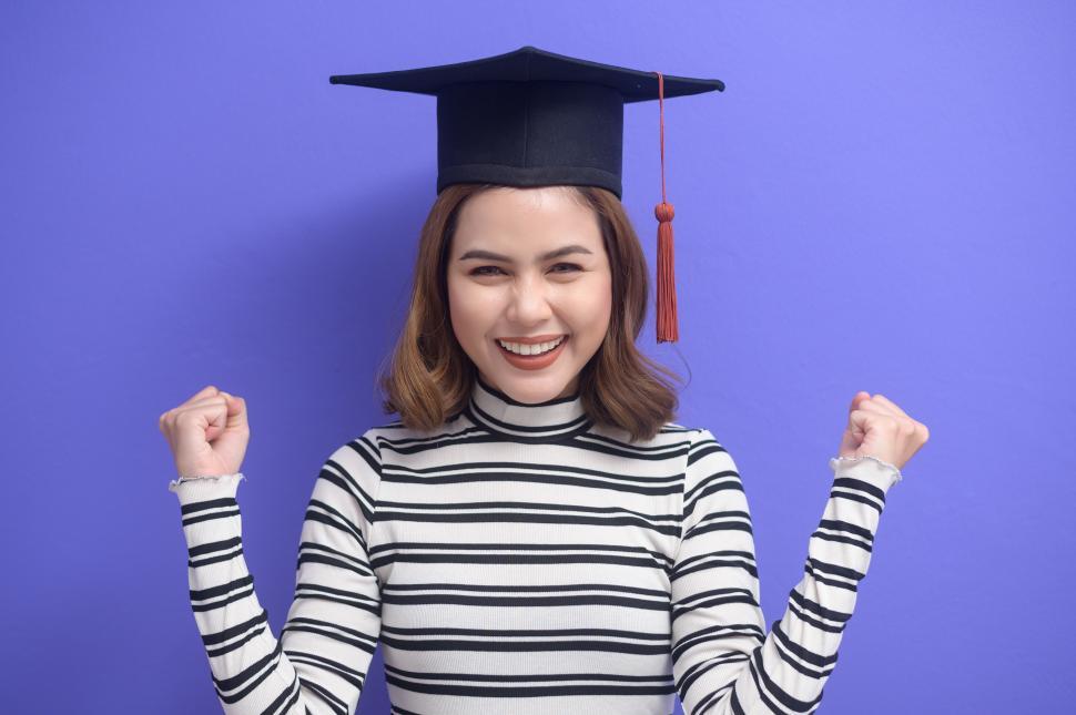 Free Image of Portrait of young woman celebrating graduation over purple background 