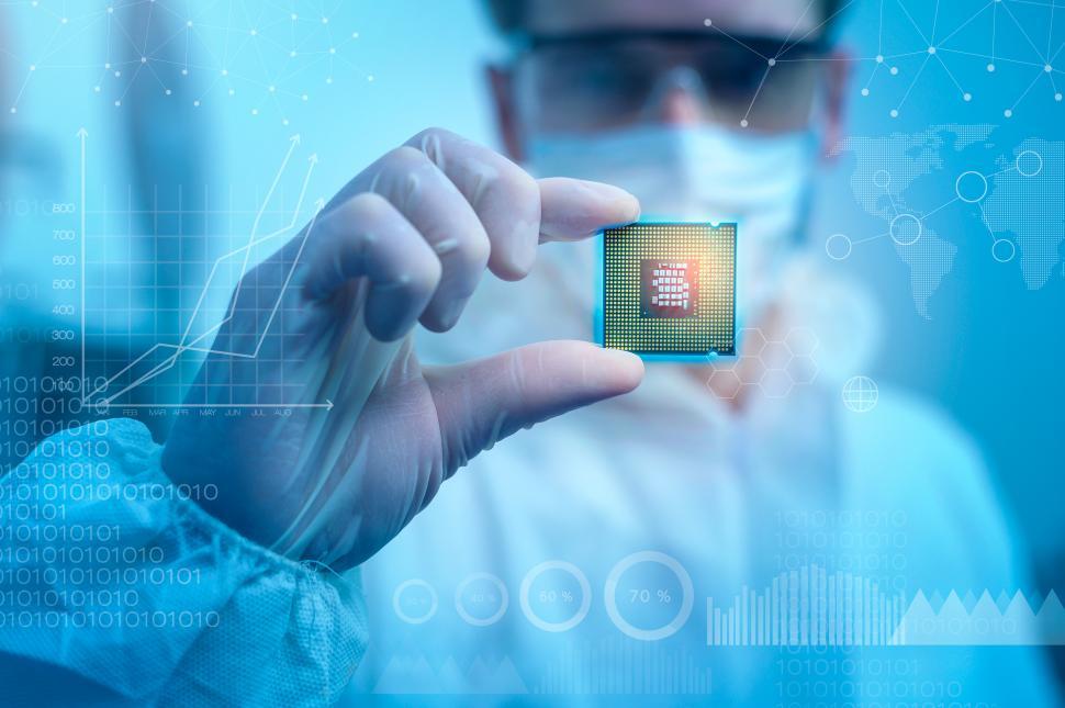 Free Image of Engineer in sterile suit is holding microchip with graphic overlays 