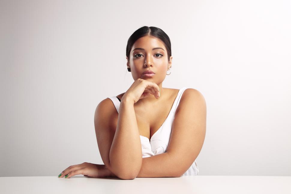 Free Image of Woman sitting with a hands on a table, studio shot 