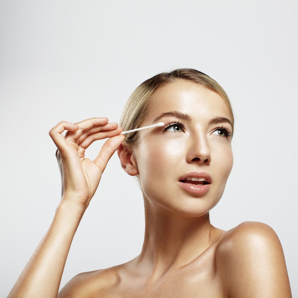 Free Image of Young woman cleansing her face with cotton swab 