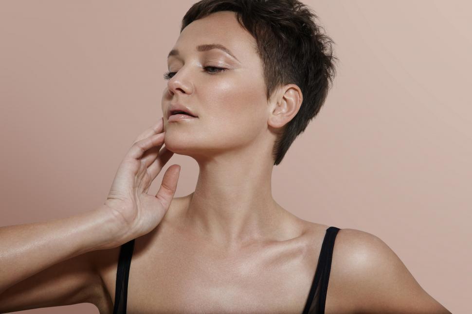 Free Image of Woman with a short haircut and ideal skin against beige background 